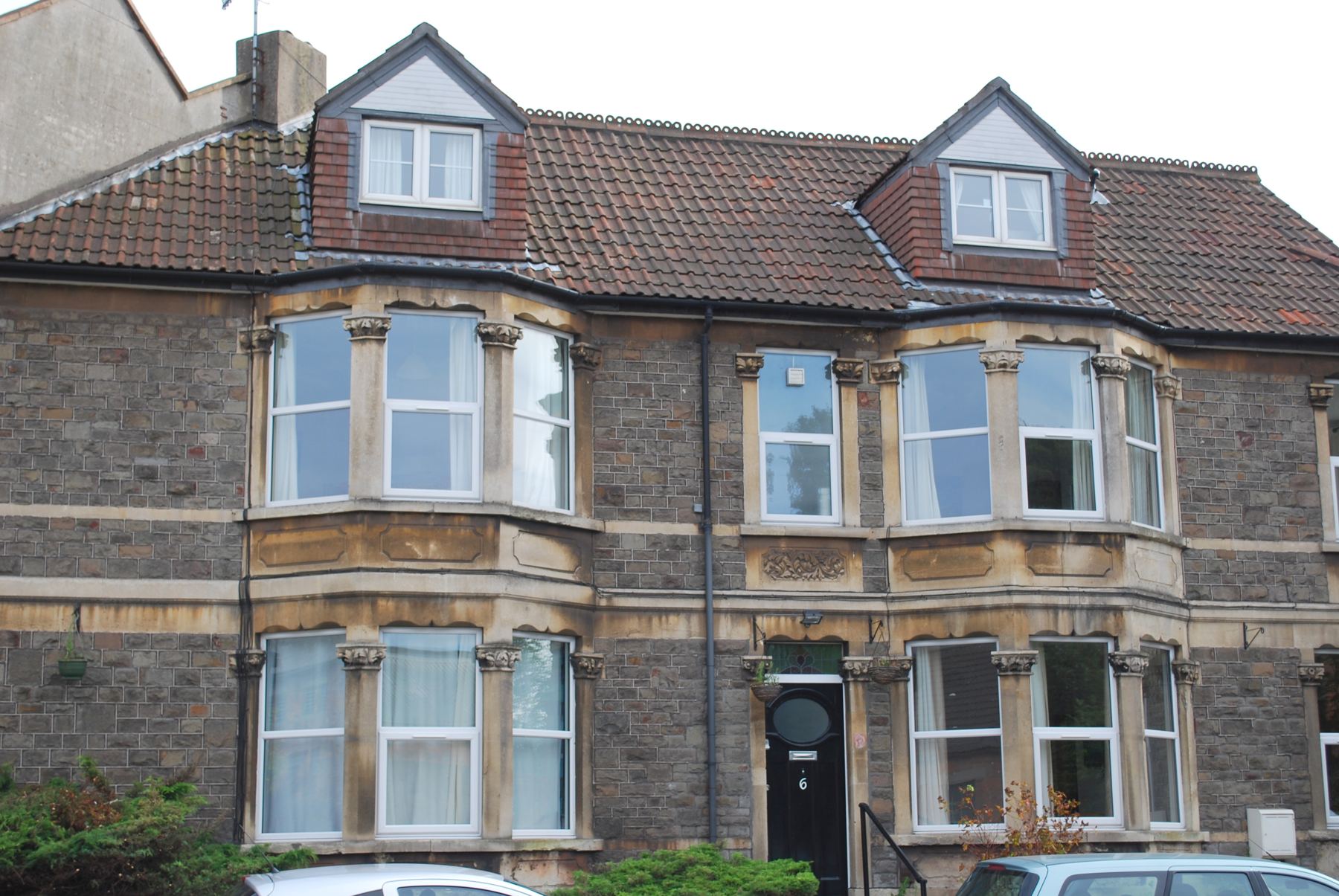 The front of Clift Guest House: a stone house with two bay windows, two dormers and a black front door numbered 6