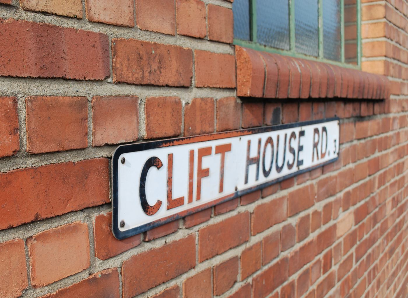 The Clift House Road street sign on a red brick wall